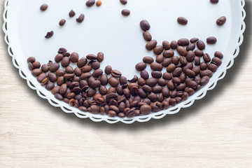 Coffee beans on a white plastic plate. On beautifull wooden background. Love. Insparation. On white plate.
