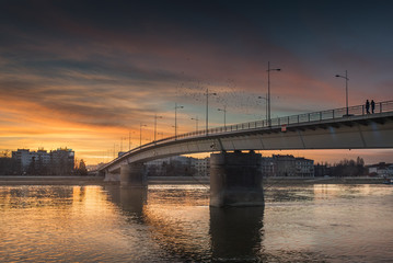 Beautiful warm sunset on the city panorama with buildings and colorful sky over the bridge and river