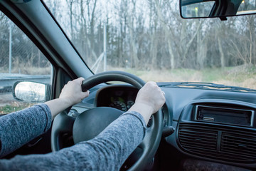 Female hand on the driving wheels. Driving a modern car steering wheel and hand close-up.
