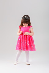 beautiful little girl in pink Princess dress with crown on gray 