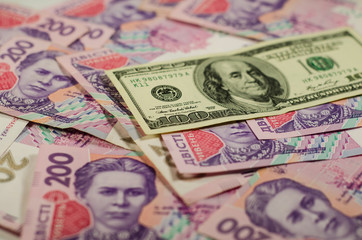 Obraz premium One hundred dollars banknote on the background of ukrainian hryvnas