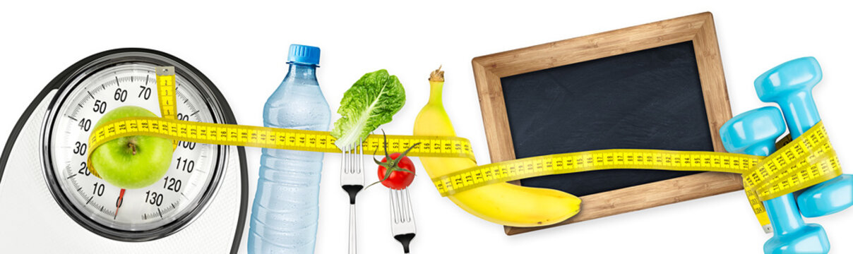 measuring tape  water bottle green apple banana dumbbell and empty slate  blackboard on white bathroom scale fitness concept panorama background / fitness waage maßband apfel tafel konzept hintergrund