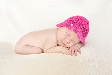 Cute sleeping newborn girl in pink hat, close-up