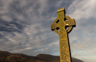 Sunlight hitting celtic cross gravestone at dawn  in rural County Kerry, Ireland