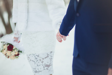 Obraz premium The bride and groom are gently holding hands at the wedding, close-up in the winter