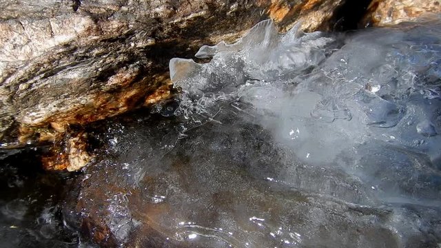 Mountain frozen stream. Thaw. Climate danger. High temperature. Water flowing