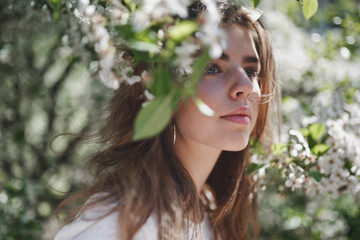 Beautiful young girl in a flowered garden, gazing into the distance.