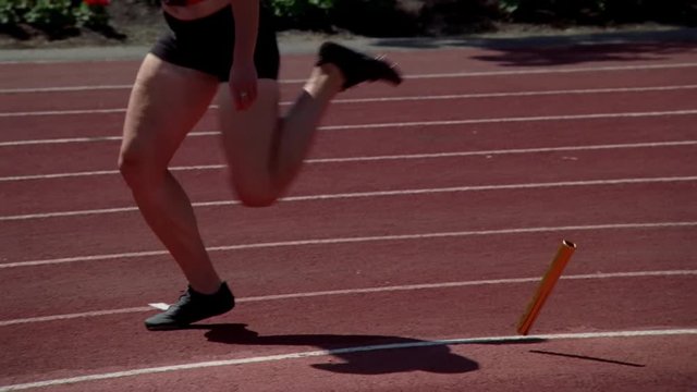 Woman relay racer dropping the baton, switch from real-time to slow motion