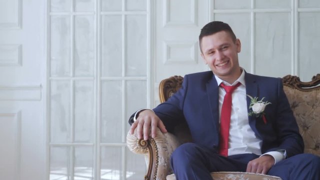 Laughing groom sits on a sofa