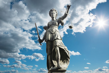 Fototapeta premium Justitia Symbol für Gerechtigkeit vor Himmel mit Wolken
