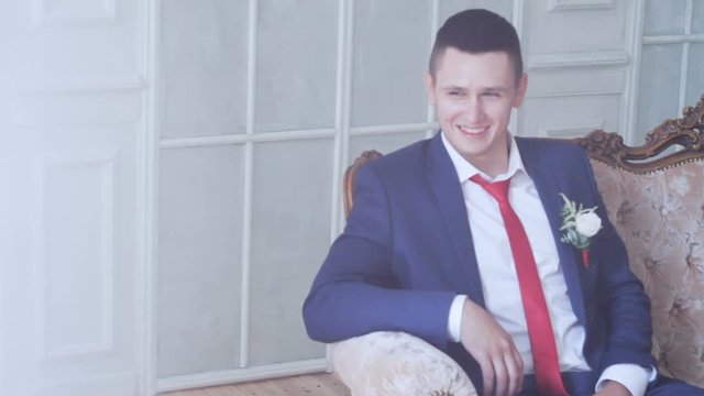 Smiling groom sits on a sofa