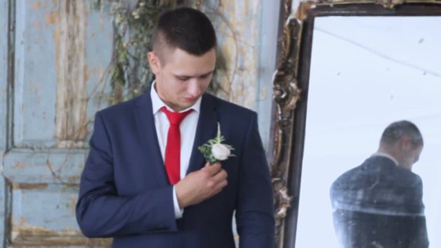 Beautiful groom preens near the mirror