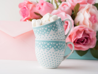 Two coffee cups with marshmallow card for Valentine's or mother woman day. Wedding baby birthday romantic date invitation. Background with roses tray romantic textile
