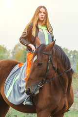 Fototapeta premium A beautiful girl is walking her horse. Focus on the girl. The warm tone of the image. Soft focus.