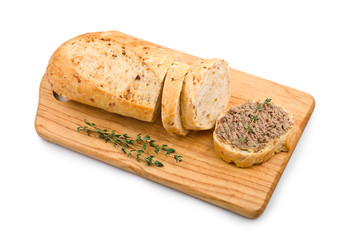 Slice of homemade bread with pate and herbs on a wooden cutting board
