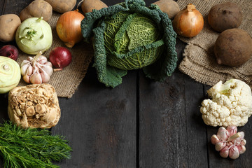 Spring vegetables on a dark background: Savoy cabbage, cauliflower, onion, garlic, kohlrabi, celery...