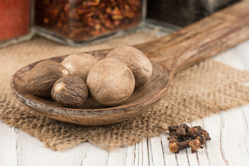 Nutmeg in a wooden spoon on old wooden table.