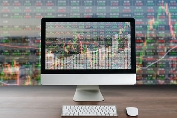Business computer on wood table showing business trading graph with cityscape building in background, Business trading technology concept