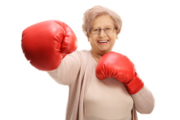 Joyful elderly woman with boxing gloves throwing a punch