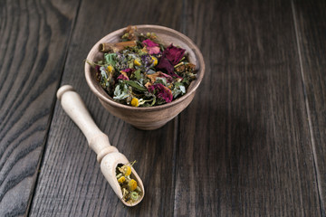 Herbal tea, herbs and flowers in a  clay cup on wooden table