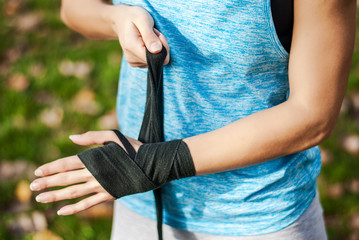 Young fitness lady putting on a sport gloves in park