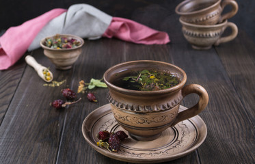 Hot cup of autumn tea with hip roses, chamomile, herbs on wooden table