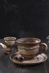 Herbal tea, herbs and flowers in a  clay cup on wooden table
