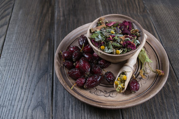 Herbal tea ingredients with hip roses, chamomile, herbs on wooden table