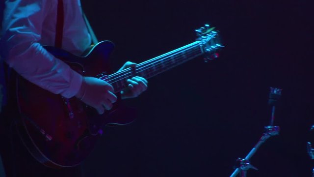 Guitarist plays guitar at concert. Close-up. Light of stroboscopes. 