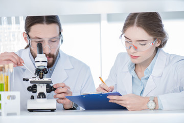 Chemists working with microscope