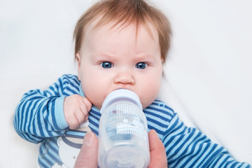 A baby drinks from a bottle of water.