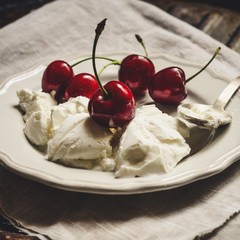 White ice cream with cherries (in a plate on the table)