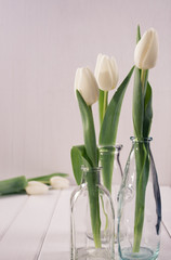 Three glass bottles with tulips in minimalistic.