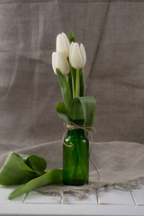White tulips in glass bottle. Home interior decoration