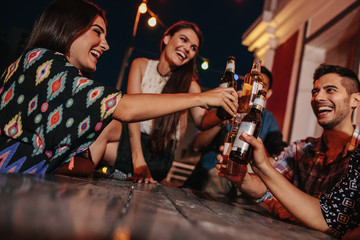 Group of friends toasting drinks at party in evening