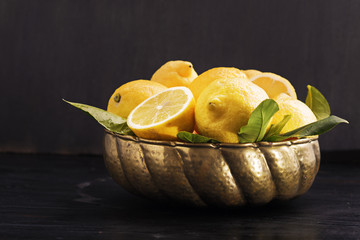 Lemons on vintage metal bowl on a black board. Selective focus.