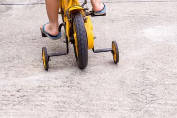 Children with slippers cycling bike with training wheels