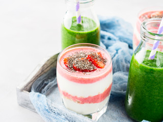 Healthy food concept green smoothie yogurt strawberries chia seeds breakfast on white gray tray blue textile. Fruit Vegetable juice glass bottle