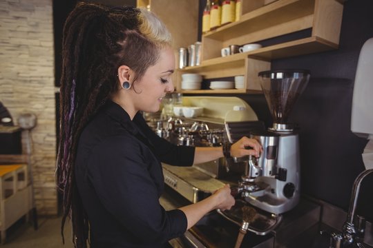 Waitress holding portafilter filled with ground coffee