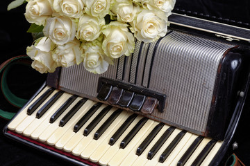 Vintage accordion and a bouquet of white roses. Concept of a nostalgic music. Still life with a...