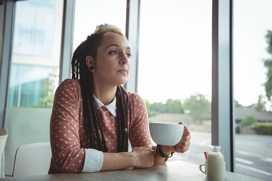 Thoughtful woman having cup of coffee