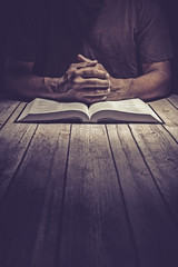 Man praying on a wooden table with an open Bible - 139955045