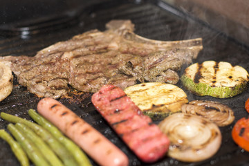 Grilled beef steak with sausage, mixed grilled vegetables. 