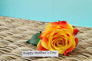 Happy Mother's day card with one colorful rose on wicker surface
