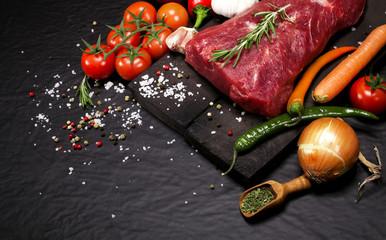 Raw beef steak on a cutting board with rosemary and spices.