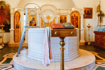 Golden religious utensils - Bible, cross, prayer book, missal, baptismal font. Details in the Orthodox Christian Church. Russia.