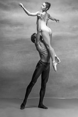 Couple of ballet dancers posing over gray background