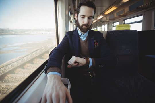 Businessman checking time on smartwatch while travelling