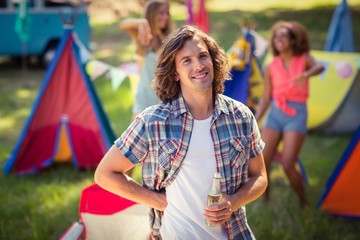 Portrait of man holding beer bottle at campsite