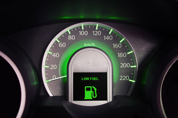 Close up dashboard of a car speed meter and low fuel signal.